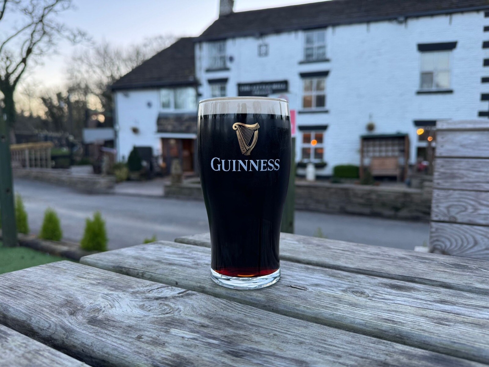 A pint of Guinness on a garden table at dusk