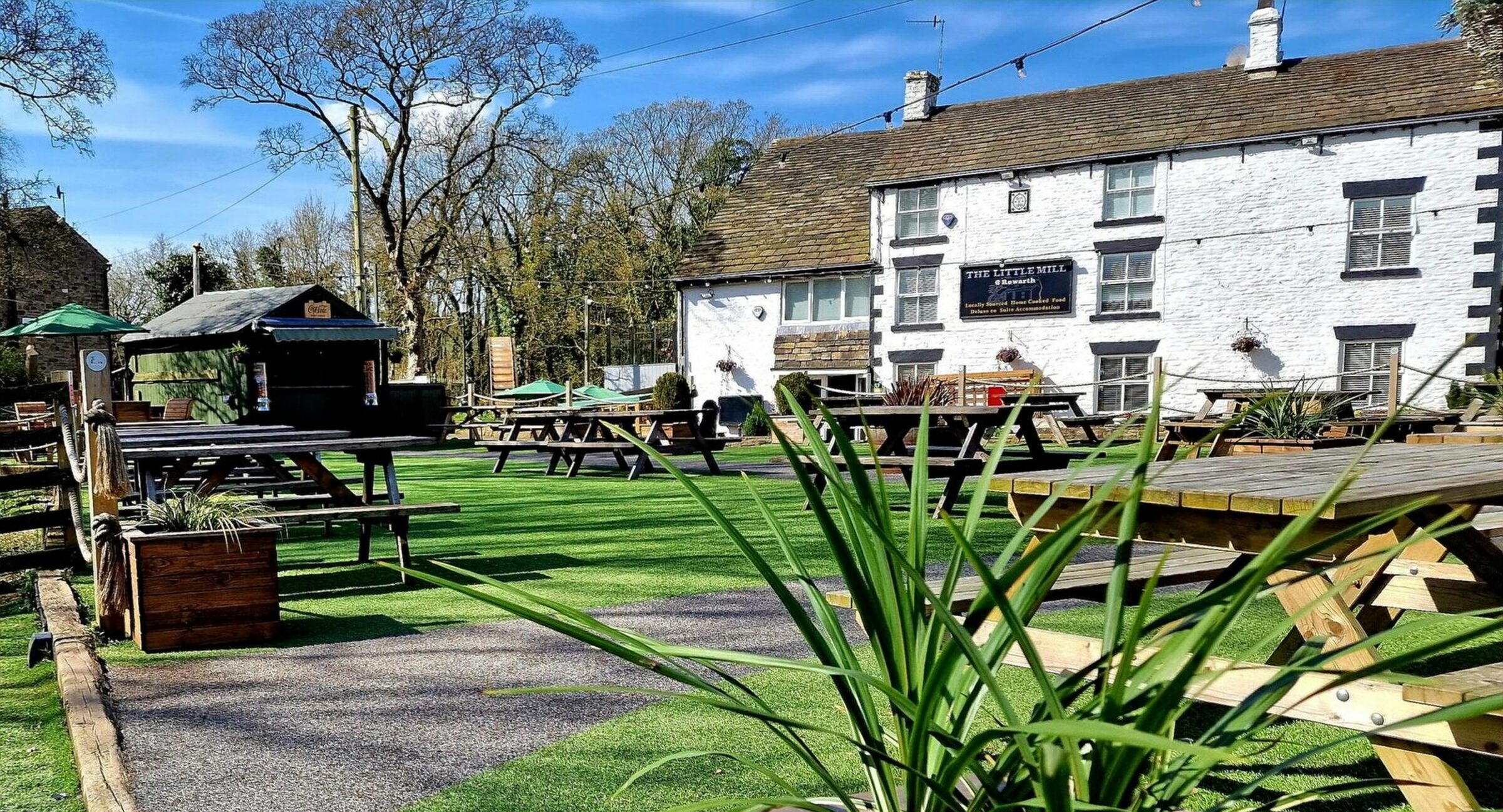 The Little Mill Inn's whitewashed exterior and garden seating in spring, Rowarth