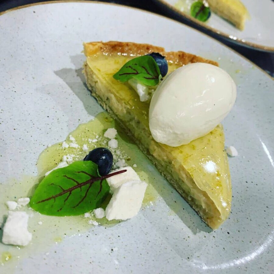 A plated dessert tart with cream and berries