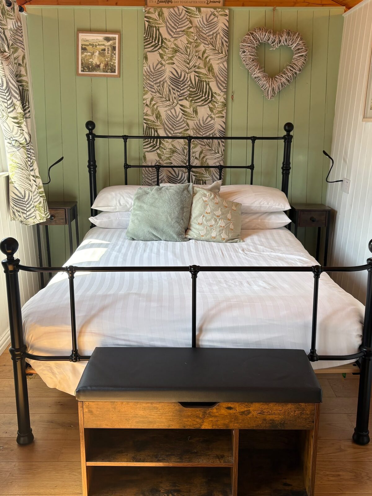 Shepherd's Hut 2 interior, double bed against a sage-green botanical feature wall