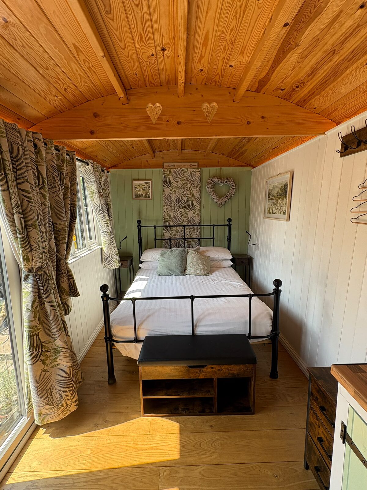 Double bed with an iron frame under the shepherd's hut's curved pine ceiling