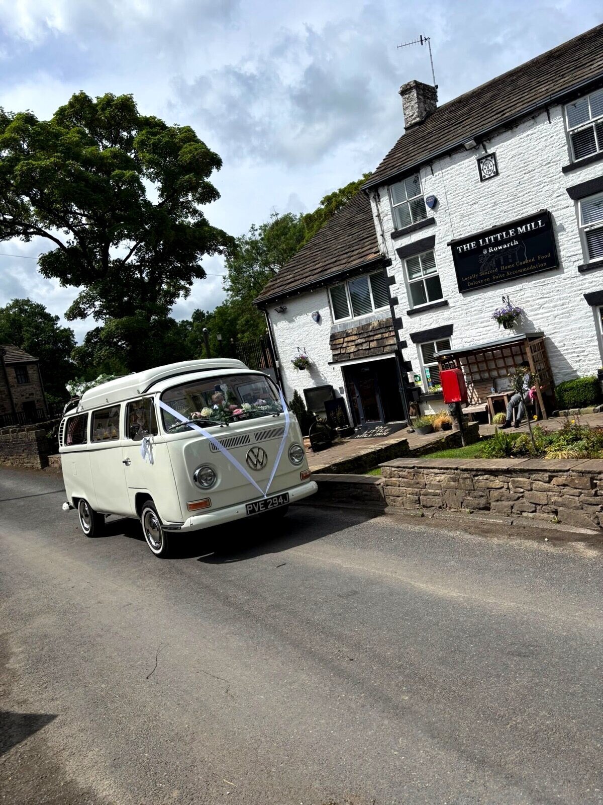 A ribbon-dressed VW campervan arriving outside The Little Mill Inn